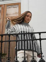 Sweater tejido a rayas horizontales color beige, marrón y negro, de cuello alto y corte holgado.