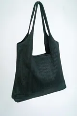 Bolso negro tipo tote bag con textura acanalada y asas de hombro.