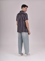 Camisa de manga corta con estampado de hojas color verde sobre fondo beige, cuello solapa y bolsillo en el pecho.