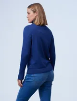 Polera de punto fino marca Nienty, color blanco, con cuello alto volcado y mangas largas con detalle de tajo en los puños.