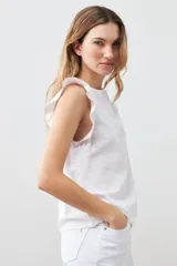 Blusa blanca sin mangas de lino con cuello redondo y volados en los hombros.