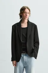 Blazer azul marino de corte recto, confeccionada en tejido con viscosa. Tiene cuello con solapas de muesca, manga larga con puño abotonado, bolsillo de vivo en el pecho y bolsillos de parche en la cadera. El bajo tiene aberturas en la espalda y el cierre es con botonadura frontal.