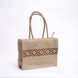 Bolso tipo shopper de yute color beige con diseño geométrico marrón en el centro. Asas cortas de soga.
