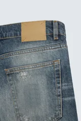 Pantalón de jean azul con efecto lavado, corte recto y largo al tobillo.