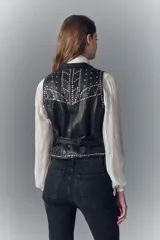 Chaleco negro de cuero ovino con tachas metálicas, botones al frente, bolsillos ojal y tira de ajuste en la espalda.