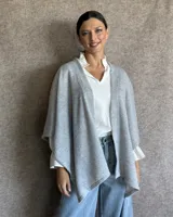 Ruana tejida en lana color gris claro, de corte amplio y diseño abierto.