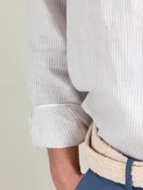 Camisa celeste a rayas verticales de lino, corte regular fit, cuello italiano, cierre con botones, manga larga terminada en puño simple y logo bordado en el pecho.