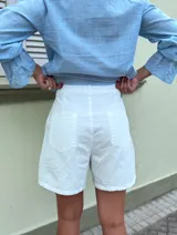 Short de gabardina color amarillo pálido, tiro alto, con pliegues frontales y bolsillos laterales.