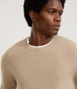 Suéter de punto color gris, con cuello redondo, manga larga y textura maquinetada.