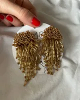 Par de caravanas colgantes doradas con cuentas tubulares y esféricas.