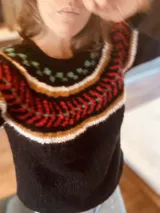 Sweater negro tejido a mano en mohair, con cuello redondo y diseño con motivos geométricos en blanco, rojo, verde y amarillo.