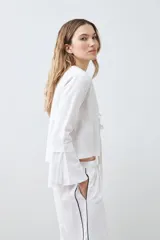 Blusa blanca de lino con escote en V y cierre frontal con lazos. Mangas largas acampanadas.