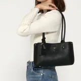 Cartera tote Guess Meridian chica color negro con doble asa de mano y dije colgante con logo de la marca.