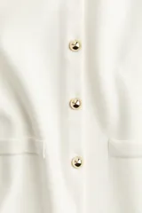 Chaleco color crema de punto fino con escote redondo, botonadura frontal dorada y bolsillos delanteros decorativos.