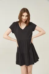 Vestido negro corto con cuello en V, manga corta y falda con volados.