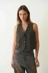 Chaleco marrón de denim con proceso de encuerado, escote en V, cierre frontal con botones y dos bolsillos con solapa y botón.