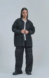 Campera negra oversize con broches en el delantero, forrada con red, múltiples bolsillos con detalles réflex y puños elásticos.