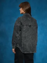 Sobrecamisa negra de denim con cuello clásico, cierre frontal con botones a presión, mangas largas con puños abotonados, dos bolsillos con solapa en el pecho y corte holgado.
