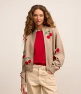 Chaqueta de punto tipo cardigan color beige con cierre de cremallera, cuello alto y estampado de cerezas.