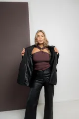 Pantalón de ecocuero negro con textura rústica, corte recto, bolsillos delanteros y traseros funcionales, cierre frontal con botón y cremallera.