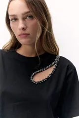 Remera negra de algodón con detalle de pedrería en forma de gota y calado en el cuello.
