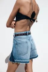 Shorts de jean de tiro medio, corte mom fit, con efecto lavado y terminación desflecada. Presenta cinco bolsillos y cierre frontal con cremallera y botón.