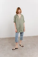 Camisa color beige de lino, con corte recto y calce suelto, cuello camisero, botones en el frente y mangas cortas con presilla y botón.