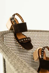 Sandalias de tacón de madera con tiras de gamuza marrón y detalles de tachas metálicas.