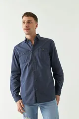 Camisa de gabardina gris con corte slim, mangas largas, cartera abotonada y dos bolsillos con solapa en el pecho.