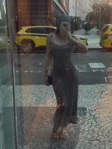 Vestido midi negro con estampado de lunares blancos, breteles finos y corte ajustado.