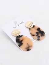 Par de aros colgantes con forma de lágrima, con estampado carey en tonos beige y negro, y pieza circular dorada en la parte superior.