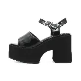 Sandalias negras de cuero sintético con plataforma alta y taco cuadrado. Presentan una tira ancha sobre los dedos y una correa ajustable con hebilla al tobillo.