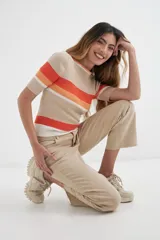Sweater de punto color beige con rayas horizontales en naranja y blanco, de mangas cortas y cuello redondo.