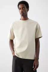 Remera color beige de algodón pesado, corte holgado, cuello redondo ribeteado, hombros caídos y bajo recto.