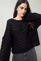 Sweater negro calado con diseño de líneas diagonales en relieve y mangas acampanadas.