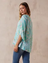 Blusa de gasa estampada marca Ruby Rd. con cuello redondo, escote en V con aplique metálico, delantera con sobre capa y terminación asimétrica. Manga ¾ amplia.