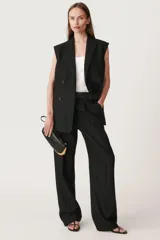 Chaleco negro oversize con cuello solapa de muescas y manga sisa. Tiene falsos bolsillos de vivo en delantero, forro interior a tono y abertura en la espalda. El cierre frontal es cruzado con botones.