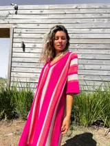 Vestido tejido a rayas verticales color fucsia, beige y rojo, con escote en V y mangas cortas.