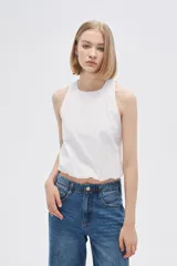 Blusa blanca de algodón sin mangas, con cuello a la base, abertura en la espalda y lazo.