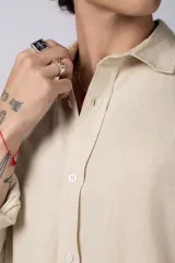 Camisa color arena de lino, manga larga, con cuello clásico y corte holgado.