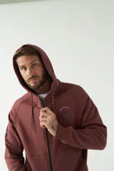 Campera de felpa color bordó con capucha y cordón ajustable, cierre frontal con cremallera, bolsillos laterales y logo estampado en el pecho.