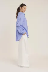 Camisa blanca de manga larga, corte holgado, con cuello camisero y detalles de bordados perforados (calado) verticales en el frente.