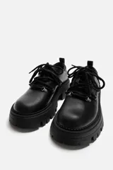 Zapato tipo derby de cuero negro con cordones y ganchos metálicos. Suela track con plataforma.