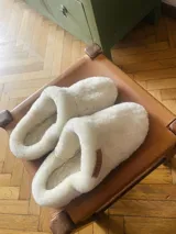 Pantuflas de corderito blancas, con interior suave y diseño cómodo para uso en casa.