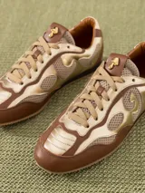 Zapatilla urbana color marrón y dorado, confeccionada en cuero vacuno con recortes en mesh.