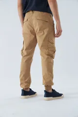 Pantalón cargo gris oscuro, corte slim, con cierre de botón y cremallera, trabillas para cinturón, bolsillos cargo con botón y puños ajustados.