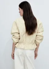 Chaqueta acolchada color verde militar con cuello perkins, cierre frontal con botones, dos bolsillos laterales y detalle fruncido en el bajo. Estilo bomber.