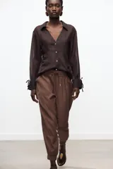 Pantalón jogger marrón de tiro alto con cintura elástica ajustable con cordones, bolsillos delanteros y puños elásticos en los tobillos.