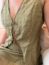 Conjunto de top y falda verde oliva con textura. El top es sin mangas, con escote en V y lazo ajustable en el centro. La falda es corta y ajustada.