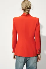 Blazer color rojo con cuello solapa, manga larga con hombreras, bolsillos delanteros con solapa y cierre frontal con botones dorados.